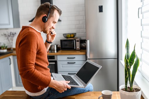 remote work man working in kitchen a man on his laptop taking a work phone call in his kitchen