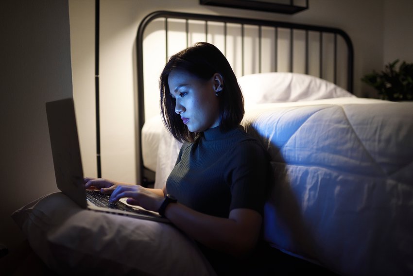 Asian woman sitting on her floor working remote on her laptop
